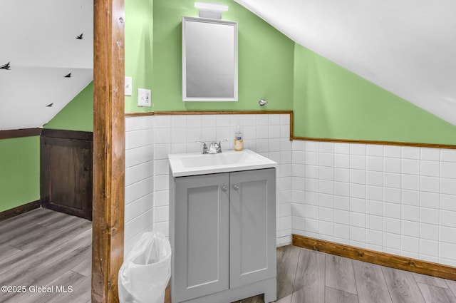 633 Moore Hill Rd, Stephentown, NY 12168 - bathroom with tile walls, lofted ceiling, vanity, wood finished floors, and wainscoting