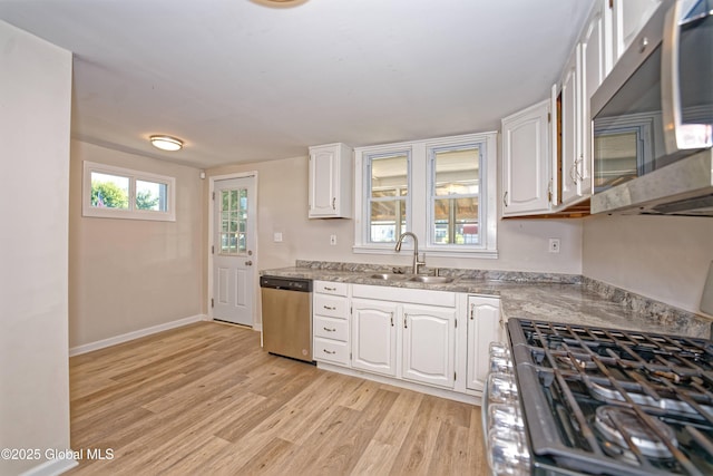 901 Adams St, Rotterdam, NY 12306 - kitchen featuring appliances with stainless steel finishes, white cabinets, light wood-style flooring, and light stone countertops