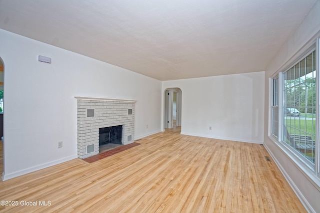 21 Crooked St, Charlton, NY 12019 - unfurnished living room with arched walkways, wood finished floors, and a brick fireplace
