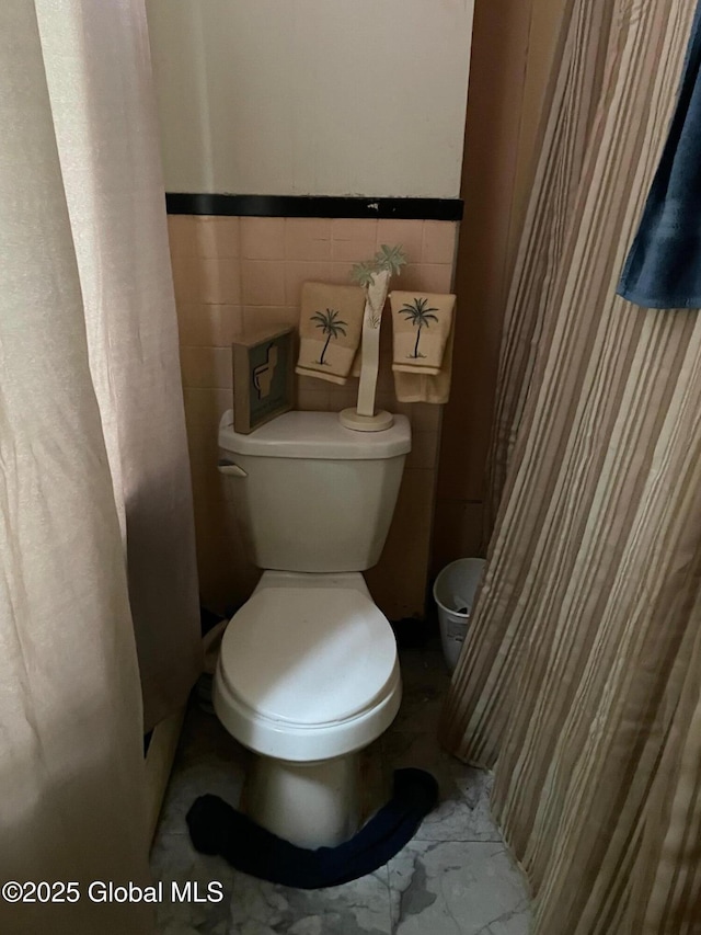 21-25 Mohawk St, Fort Plain, NY 13339 - bathroom featuring wainscoting, marble look tile flooring, and curtained shower