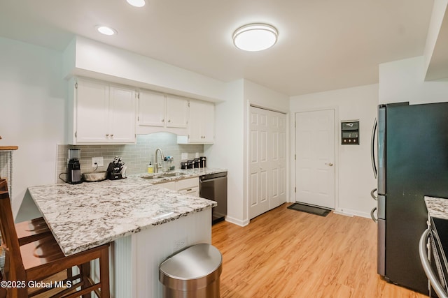 22 Pine Ridge Rd, Stillwater, NY 12866 - kitchen with appliances with stainless steel finishes, a peninsula, white cabinets, light wood-style flooring, and backsplash