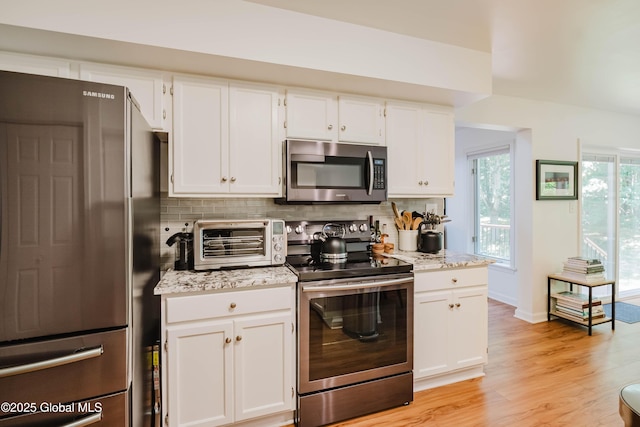 22 Pine Ridge Rd, Stillwater, NY 12866 - kitchen featuring stainless steel appliances, tasteful backsplash, white cabinetry, light wood-style floors, and light stone counters