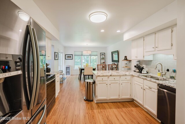 22 Pine Ridge Rd, Stillwater, NY 12866 - kitchen with appliances with stainless steel finishes, a peninsula, white cabinets, light wood-style floors, and backsplash