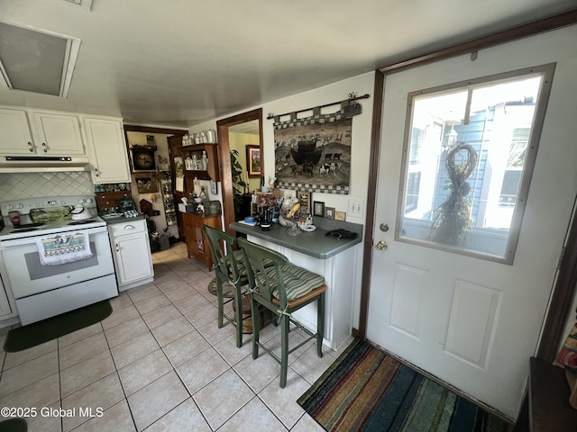 56 Wendell St, Ravena, NY 12143 - kitchen with electric stove, white cabinets, under cabinet range hood, backsplash, and light tile patterned floors
