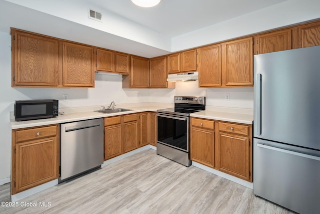 24 Esplande St, Bethlehem, NY 12158 - kitchen with stainless steel appliances, under cabinet range hood, light countertops, and brown cabinetry