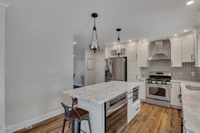 139 Country Walk Rd, Rotterdam, NY 12306 - kitchen with wall chimney range hood, stainless steel appliances, light wood-style floors, white cabinets, and tasteful backsplash