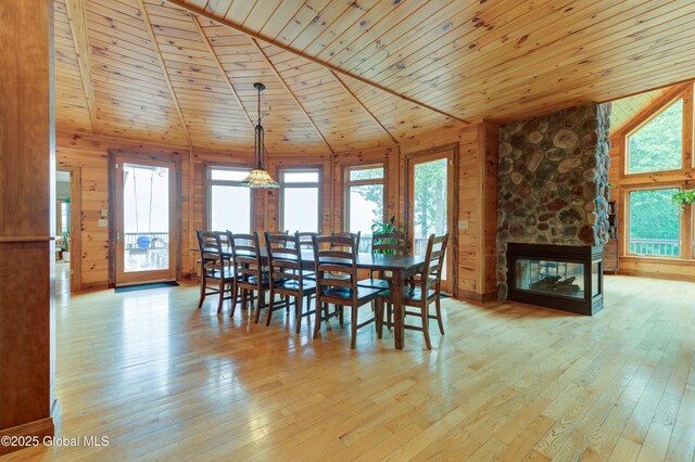 102 Taylor Ct, Mayfield, NY 12117 - dining space with lofted ceiling, hardwood / wood-style flooring, wooden ceiling, wooden walls, and a stone fireplace
