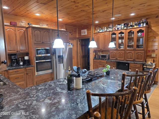 102 Taylor Ct, Mayfield, NY 12117 - kitchen with appliances with stainless steel finishes, wooden ceiling, a breakfast bar area, brown cabinetry, and wood walls