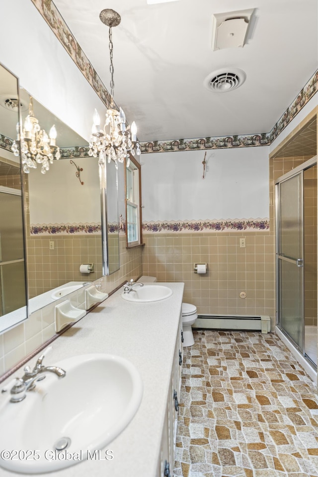 654 Birchwood Dr, Princetown, NY 12056 - bathroom with tile walls, baseboard heating, double vanity, a shower stall, and a chandelier