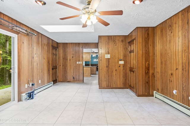 654 Birchwood Dr, Princetown, NY 12056 - unfurnished room featuring a baseboard heating unit, ceiling fan, wood walls, and a textured ceiling