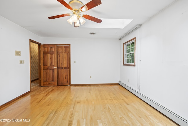 654 Birchwood Dr, Princetown, NY 12056 - empty room with a baseboard heating unit, a skylight, light wood-style floors, and a ceiling fan