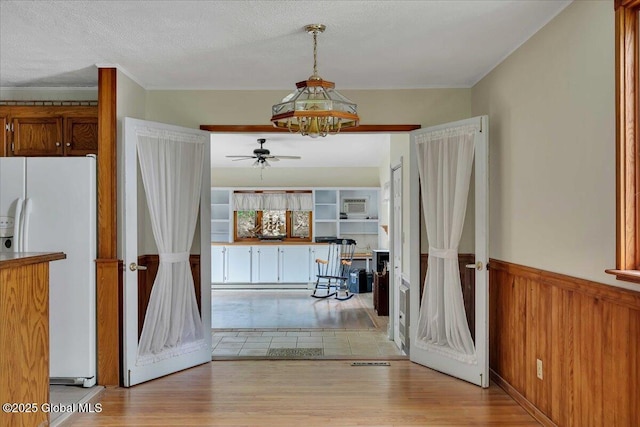 273 Pinehurst Ave, East Greenbush, NY 12144 - kitchen with white refrigerator with ice dispenser, ceiling fan, light wood-type flooring, wainscoting, and brown cabinets