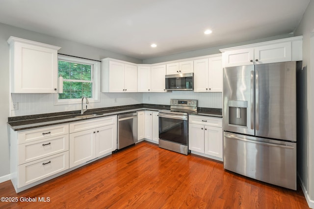 5 Heather Ln, Corinth, NY 12822 - kitchen with appliances with stainless steel finishes, white cabinetry, dark wood-type flooring, backsplash, and recessed lighting