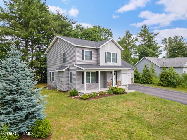 5 Heather Ln, Corinth, NY 12822 - view of front of property with a porch, driveway, a front lawn, a garage, and stone siding