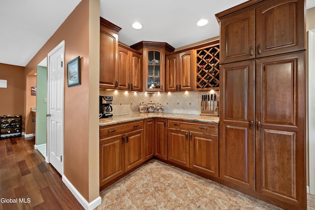 658 Salvia Ln, Guilderland, NY 12303 - kitchen featuring light stone countertops, decorative backsplash, glass insert cabinets, brown cabinets, and recessed lighting