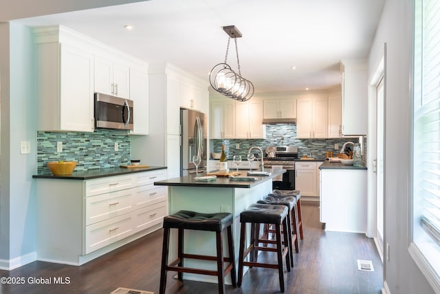 12 Heritage Ln, Clifton Park, NY 12065 - kitchen with appliances with stainless steel finishes, dark countertops, a kitchen island with sink, decorative backsplash, and recessed lighting
