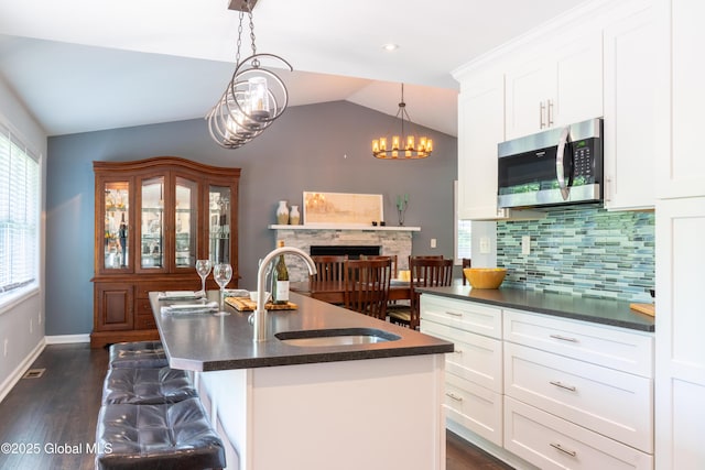 12 Heritage Ln, Clifton Park, NY 12065 - kitchen featuring stainless steel microwave, dark countertops, vaulted ceiling, white cabinets, and backsplash