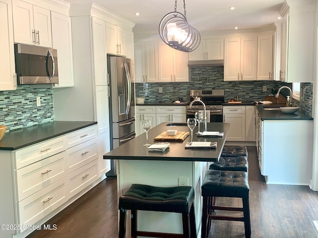 12 Heritage Ln, Clifton Park, NY 12065 - kitchen featuring stainless steel appliances, dark countertops, a kitchen island with sink, a breakfast bar, and recessed lighting