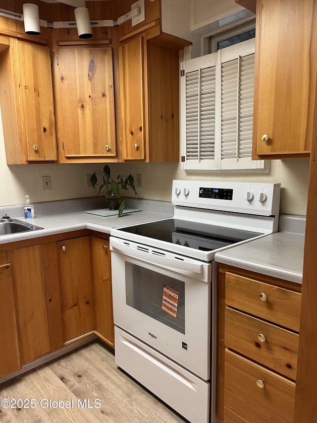59 W St, Whitehall Village, NY 12887 - kitchen with white electric range oven, light countertops, light wood-style floors, and brown cabinets