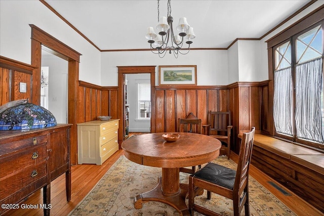 1280 Dean St, Niskayuna, NY 12309 - dining room with light wood-type flooring, wainscoting, a chandelier, and crown molding