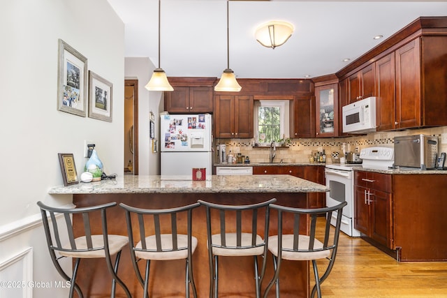 2 Eddy Ln, East Greenbush, NY 12144 - kitchen featuring white appliances, a peninsula, a kitchen breakfast bar, tasteful backsplash, and light stone countertops