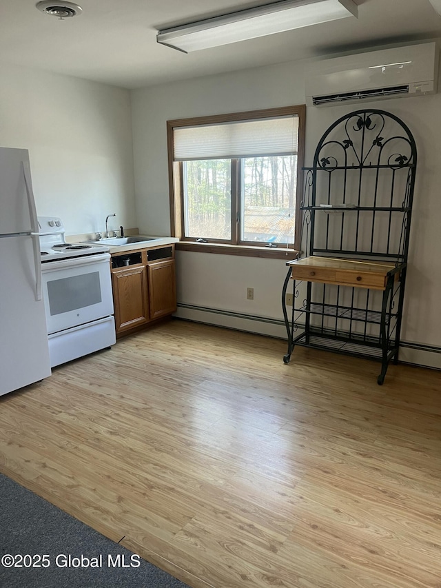 336 State Route 29, Greenwich, NY 12834 - kitchen with white appliances, a wall mounted AC, light wood-style floors, brown cabinets, and baseboard heating