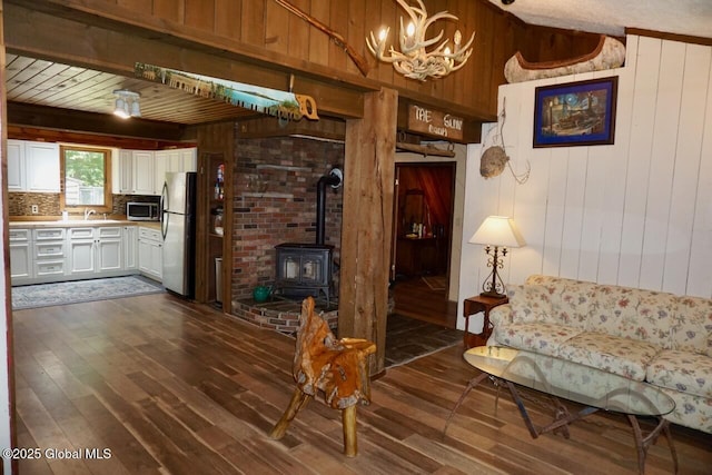 469 Military Rd, Edinburg, NY 12134 - living room featuring wood walls, dark wood-style floors, a wood stove, and a chandelier