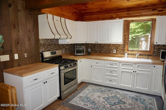 469 Military Rd, Edinburg, NY 12134 - kitchen with stainless steel range with gas stovetop, ventilation hood, vaulted ceiling, decorative backsplash, and wood counters