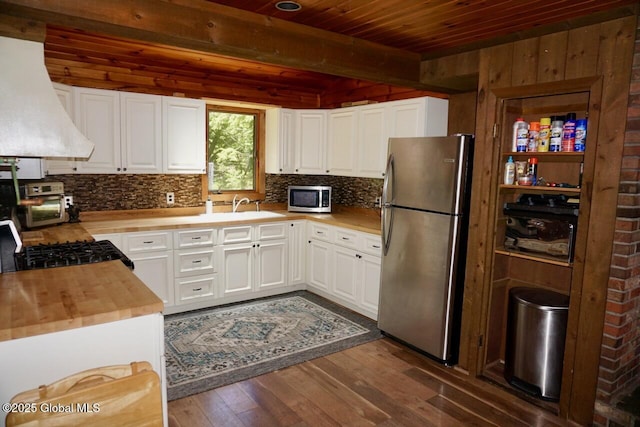 469 Military Rd, Edinburg, NY 12134 - kitchen with stainless steel appliances, wall chimney exhaust hood, dark wood-type flooring, butcher block counters, and a wood ceiling with exposed beams