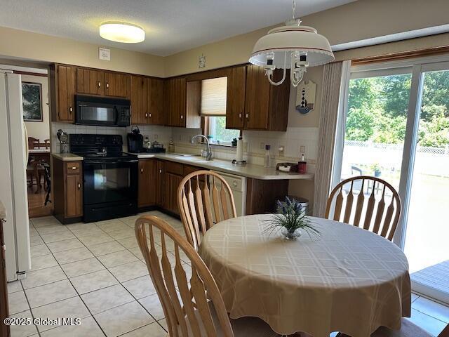 12 Bain Dr, Bethlehem, NY 12054 - kitchen with black appliances, decorative backsplash, light countertops, and light tile patterned flooring