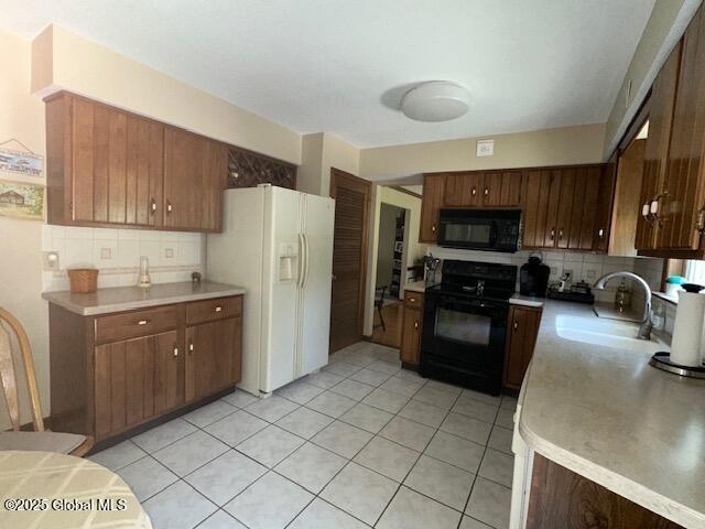 12 Bain Dr, Bethlehem, NY 12054 - kitchen featuring black appliances, decorative backsplash, light countertops, and light tile patterned floors