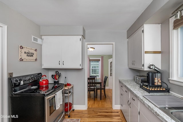 30 Crannell Ave, Bethlehem, NY 12054 - kitchen with electric stove, light wood-style flooring, white cabinets, and light stone counters