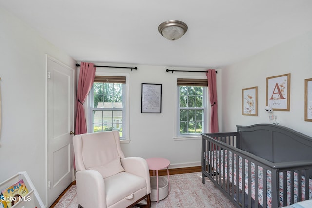 30 Crannell Ave, Bethlehem, NY 12054 - bedroom featuring multiple windows, a nursery area, and wood finished floors