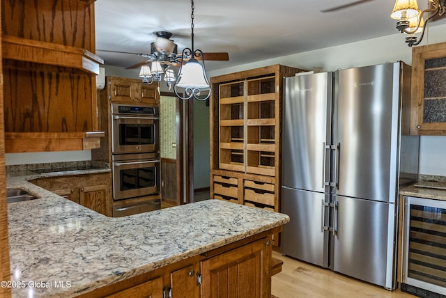 8 Burning Bush Blvd, Clifton Park, NY 12019 - kitchen featuring stainless steel appliances, beverage cooler, brown cabinets, a warming drawer, and light stone countertops