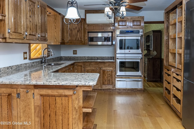 8 Burning Bush Blvd, Clifton Park, NY 12019 - kitchen featuring a warming drawer, appliances with stainless steel finishes, brown cabinets, an AC wall unit, and a ceiling fan