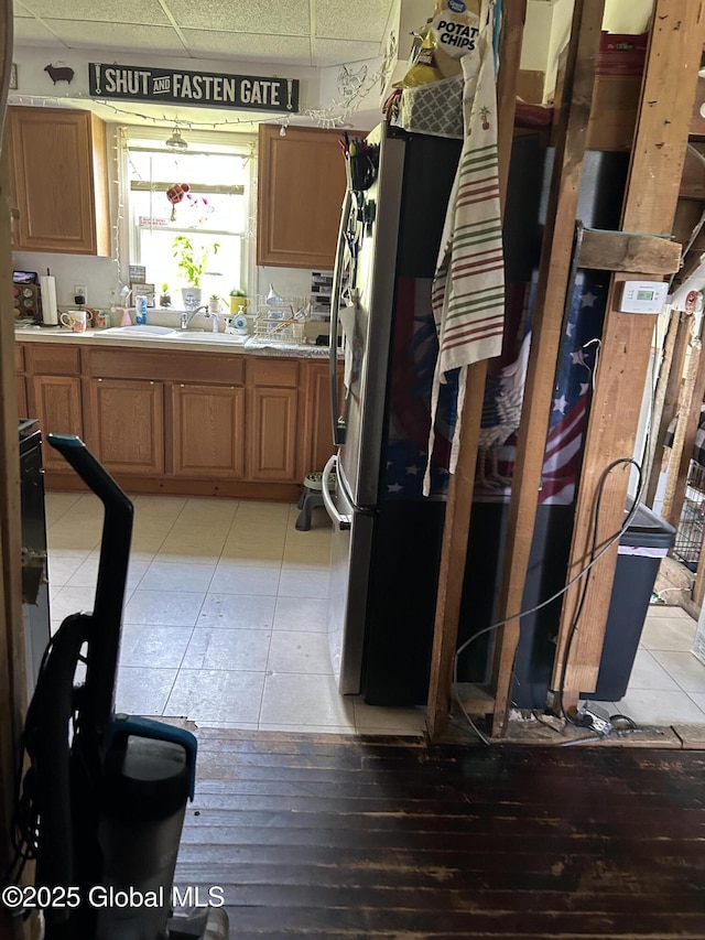 200 State Route 29a, Salisbury, NY 13454 - kitchen featuring freestanding refrigerator, a paneled ceiling, light countertops, light tile patterned floors, and brown cabinetry