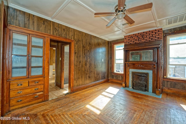 850 Peoples Ave, Troy, NY 12180 - unfurnished living room with a large fireplace, healthy amount of natural light, wooden walls, a ceiling fan, and wood finished floors