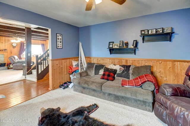 1330 State Highway 67, Johnstown, NY 12095 - carpeted living room featuring wood walls, ceiling fan, stairs, wainscoting, and wood finished floors
