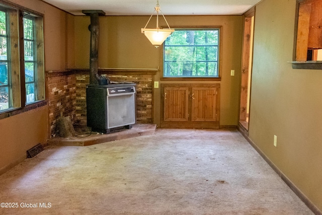 1072 Honey Hollow Rd, New Baltimore, NY 12058 - unfurnished dining area with healthy amount of natural light, a wood stove, and carpet floors