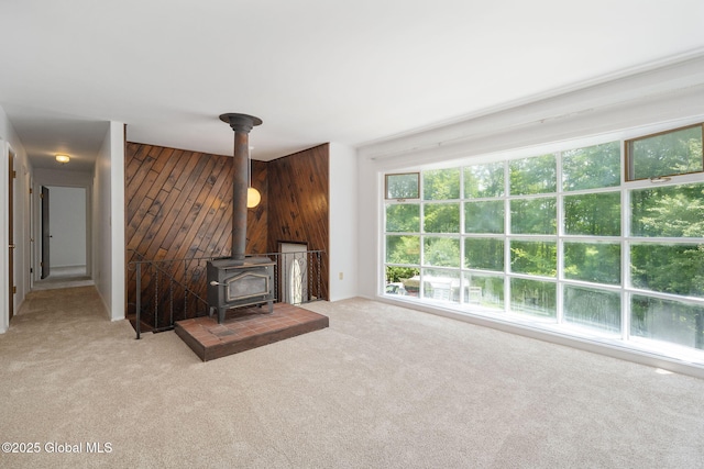 257 Lake Rd, Cobleskill, NY 12043 - unfurnished living room featuring a wood stove, wooden walls, and carpet
