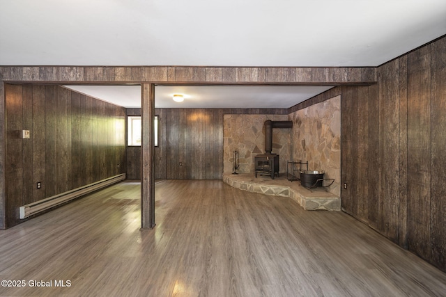 257 Lake Rd, Cobleskill, NY 12043 - below grade area featuring a baseboard heating unit, wooden walls, a wood stove, and wood finished floors