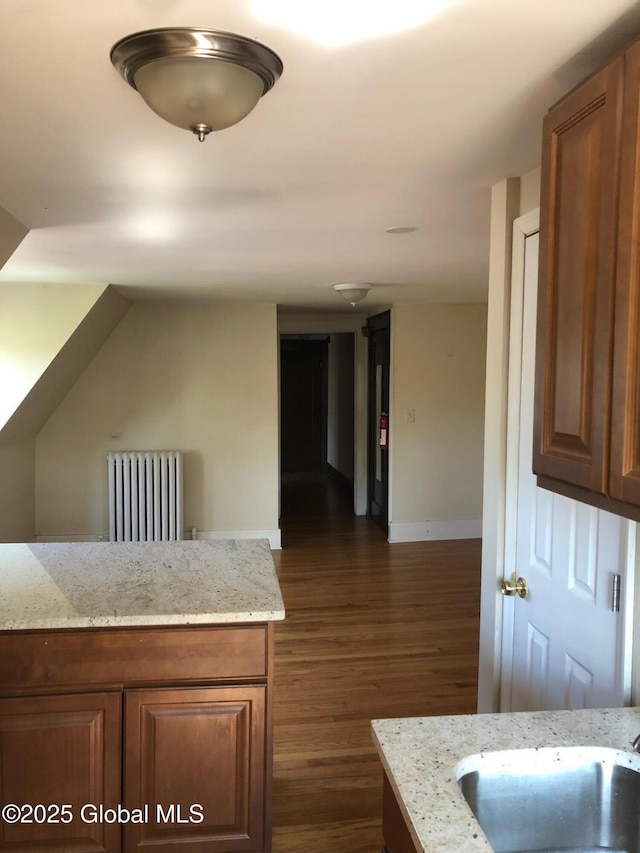 302-304 Quail St, Albany, NY 12208 - kitchen featuring radiator, dark wood-style flooring, light stone counters, and brown cabinetry