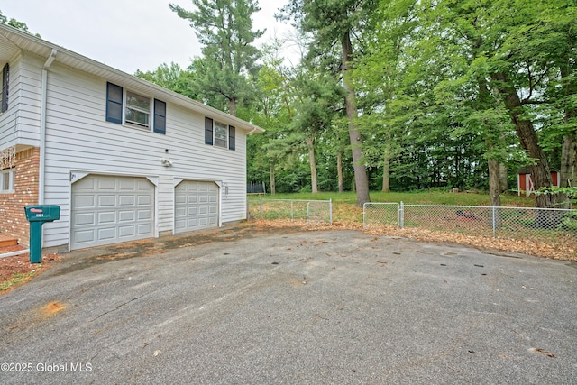 1101 Manas Dr, Schenectady, NY 12303 - view of property exterior featuring driveway, a garage, view of scattered trees, and brick siding