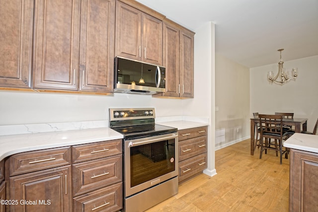 614 Apex Ln, Troy, NY 12182 - kitchen featuring stainless steel appliances, light wood finished floors, a chandelier, and decorative light fixtures