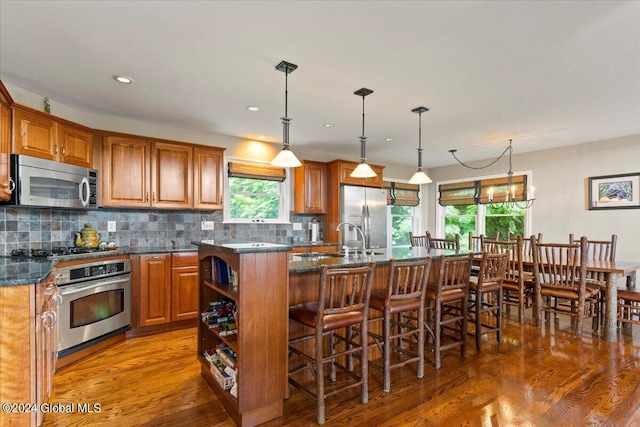 15 Green Harbour Ln, Lake George, NY 12845 - kitchen with appliances with stainless steel finishes, a center island with sink, open shelves, a breakfast bar area, and brown cabinets
