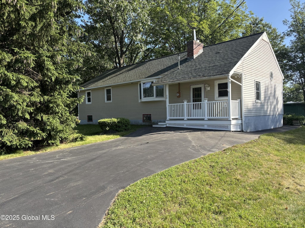 15 Merrill St, Colonie, NY 12205 - view of front facade featuring a chimney, a front yard, roof with shingles, covered porch, and driveway
