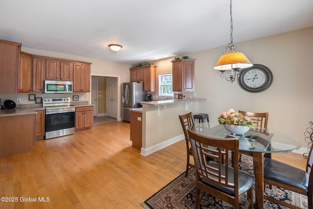 16 Callaway Cir, Colonie, NY 12211 - kitchen featuring stainless steel appliances, a peninsula, light wood-type flooring, light countertops, and hanging light fixtures