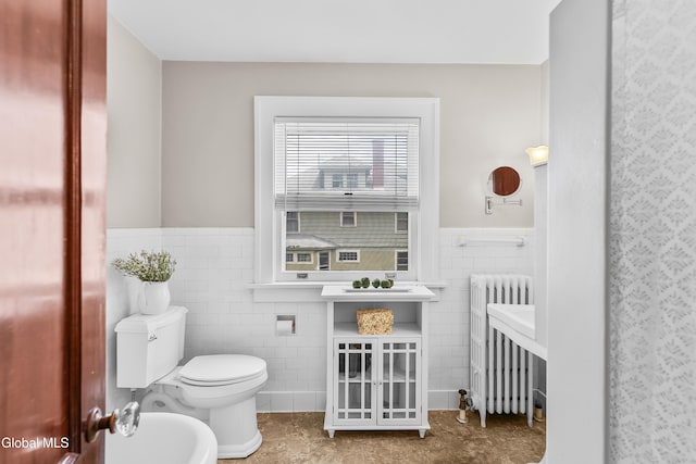 1101 Ardsley Rd, Schenectady, NY 12308 - bathroom featuring radiator, tile walls, a bidet, a wainscoted wall, and tile patterned floors