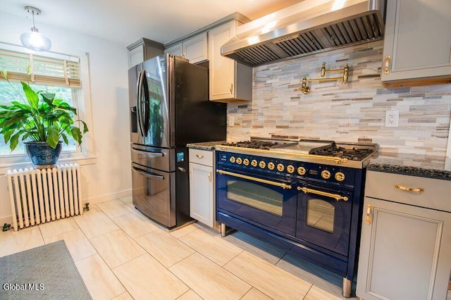 1264 Pilot Knob Rd, Fort Ann, NY 12844 - kitchen with double oven range, radiator heating unit, wall chimney range hood, stainless steel fridge, and dark stone countertops