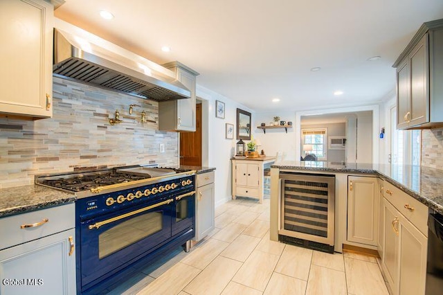 1264 Pilot Knob Rd, Fort Ann, NY 12844 - kitchen with beverage cooler, range with two ovens, wall chimney range hood, dark stone counters, and backsplash